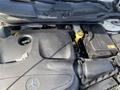 The engine compartment of a 2014 Mercedes-Benz CLA-Class showing the engine cover battery and various components