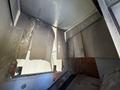 Interior view of a damaged 2011 Freightliner M2 106 showing exposed metal panels and a large opening allowing light to enter