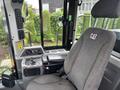 The interior of a 2012 Caterpillar 980 featuring a driver seat control panel with various buttons and levers