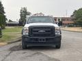 A white 2014 Ford F-550 with a black grille and multiple lights on the roof is facing forward