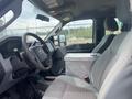 Interior view of a 2014 Ford F-350 SD showing the driver's seat steering wheel and dashboard with a metal storage box on the passenger seat