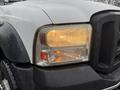 Close-up of a 2006 Ford F-450 headlight with rain droplets on its surface showcasing a clear lens and separate turn signal light