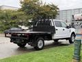 A 2019 Ford F-350 Super Duty with a flatbed truck design is parked, featuring a white exterior and chrome wheels