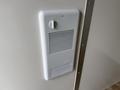 A white wall-mounted ventilation grille with a round dial for adjusting airflow