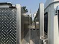 A close-up view of a 1999 Freightliner FL80 showcasing the diamond plate storage compartments and metallic surface of the truck's cargo area