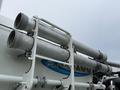 A 2013 International Workstar 7500 with two large silver pipes mounted on the side featuring a white supporting frame