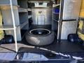 A 2016 Ford Transit 150 with a spare tire in the center and metal shelving units on either side