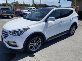 A 2018 Hyundai Santa Fe in white with a sleek design featuring alloy wheels and modern headlights