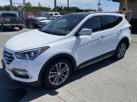 A 2018 Hyundai Santa Fe in white with a sleek design featuring alloy wheels and modern headlights