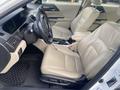 Interior of a 2017 Honda Accord Hybrid featuring beige leather seats a steering wheel and a console with gear shift and controls