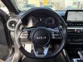 Steering wheel of a 2024 Kia Forte5 featuring a Kia logo and control buttons for audio and cruise functions