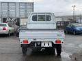 A white 2009 Suzuki Carry truck with a flatbed and cab visible from the rear angle