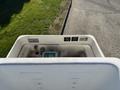 Top view of a 2005 Freightliner M2 106 truck's engine compartment showing gauges buttons and a cover in a clean white finish