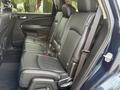 The interior of a 2013 Dodge Journey showing the backseat with black leather upholstery and adjustable headrests