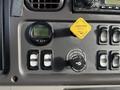 Dashboard of a 2015 Freightliner M2 featuring a digital display for average speed a yellow parking brake switch and controls for suspension adjustments