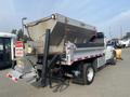 A 2016 RAM 5500 truck with a large salt spreader attached to the back featuring a rusted container and a caution sign indicating to keep back 15 meters