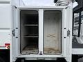 A white 2015 Freightliner M2 truck with open double doors revealing an empty storage compartment featuring two shelves and hooks on the inside walls