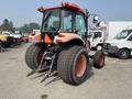 A 2010 Kubota M6040 tractor with large rear tires and a pink cab facing away from the viewer