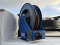 A blue hose reel with a brown hose coiled inside it mounted on a surface with a textured finish