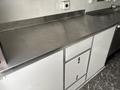 A stainless steel countertop with a gray base featuring two cabinets below one of which has a lock visible on the door