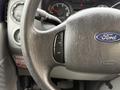 A close-up view of the steering wheel and control buttons of a 2009 Ford Econoline showing the Ford logo and various toggle switches