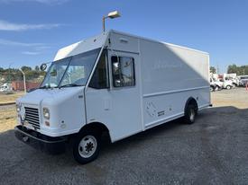 A white 2012 Ford Econoline delivery truck with a boxy structure and large front windows parked in a lot
