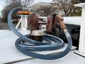 A fuel pump with a red housing attached to a blue hose resting on top of a white truck's roof