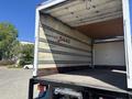 A 2022 Isuzu NQR truck with an empty cargo area featuring wooden flooring and metal railings along the sides