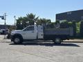 A white 2016 RAM 5500 truck with a flatbed and side compartments parked on a lot