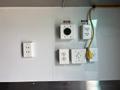 A panel with various electrical outlets and plugs labeled with "DANGER" signs including a 115V socket and multiple standard electrical outlets