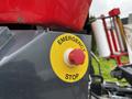 A close-up of an emergency stop button on a machine featuring a red knob on a yellow circular background labeled as emergency stop