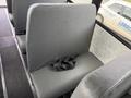 Interior view of a bus showing a gray vinyl seat with a seatbelt attached