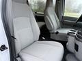 Interior of a 2013 Ford E-350 showing two gray fabric front seats and a central console with cup holders