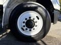 Close-up of a white wheel with multiple black lug nuts mounted on a 2012 Freightliner M2 106 truck tire