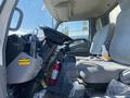 Interior of a 2014 Hino 195 featuring a driver's seat, steering wheel, and various items including a fire extinguisher and a container on the floor