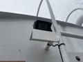 A black camera mounted on a white bracket attached to a vehicle