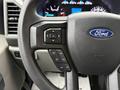 Steering wheel of a 2022 Ford F-550 featuring control buttons for audio and cruise functions with the Ford logo prominently displayed in the center