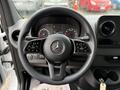 Steering wheel of a 2023 Mercedes-Benz Sprinter with various controls and the Mercedes-Benz logo prominently displayed in the center