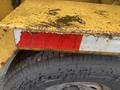 A section of a yellow Vermeer Corporation BC1000XL with a damaged edge revealing red reflective material and a nearby tire on the underside
