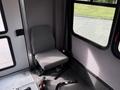 Interior view of a 2014 Ford Econoline showing a single gray fabric seat next to a window with seatbelt and floor detailing visible