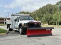A white 2007 Ford F-450 with a red snow plow attachment at the front parked on a paved surface