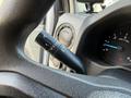 A close-up of the control stalk for windshield wipers on a 2023 Ford E-450 featuring symbols for different wiper settings and illuminated gauges in the background
