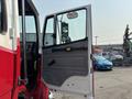A red and white 1999 Freightliner FL80 with its driver's side door open revealing the interior and driver's seat