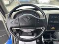 Steering wheel of a 2013 International DuraStar 4300 with control buttons and dashboard gauges visible in the background