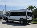 A white 2021 RAM Promaster van with black accents and large windows parked at an angle showing its side and rear view