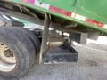 A 1997 Freightliner FL70 showing the underside with a visible black storage compartment and a pair of large tires nearby