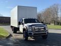 A white 2010 Ford F-450 truck with a large box cargo area is parked at an angle, showcasing its front profile and large wheels
