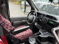 The interior of a 2015 Ford Econoline featuring a patterned driver's seat a steering wheel and various controls on the dashboard