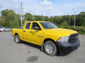 A yellow 2015 RAM 1500 pickup truck with a regular cab and a short bed is parked on a gravel surface