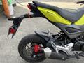 A 2018 Honda Grom in bright yellow with a sporty design showcasing its rear end and exhaust system
